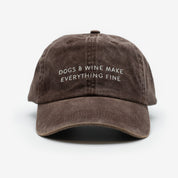 A brown denim cap with the text 'DOGS & WINE MAKE EVERYTHING FINE' embroidered on the front.