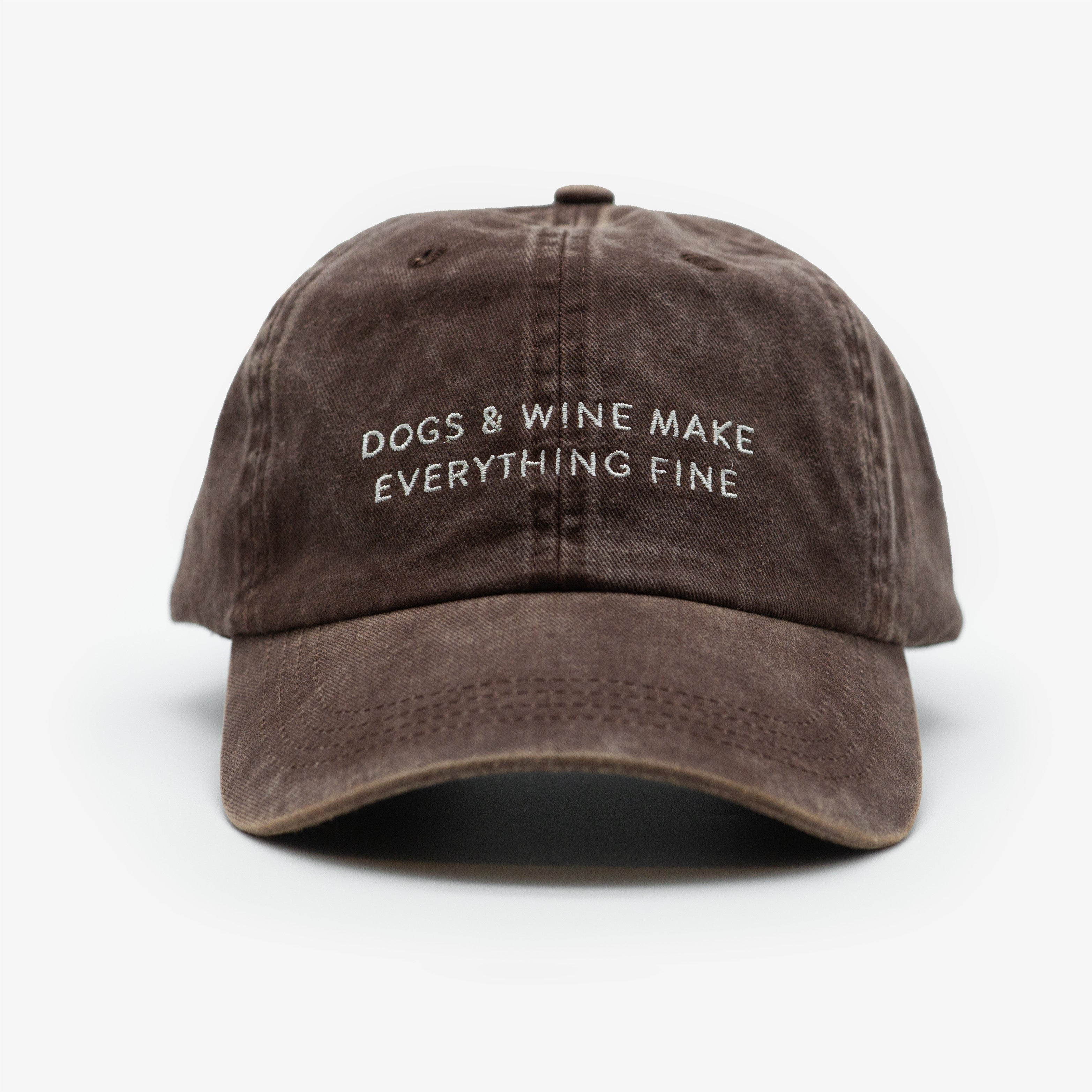 A brown denim cap with the text 'DOGS & WINE MAKE EVERYTHING FINE' embroidered on the front.