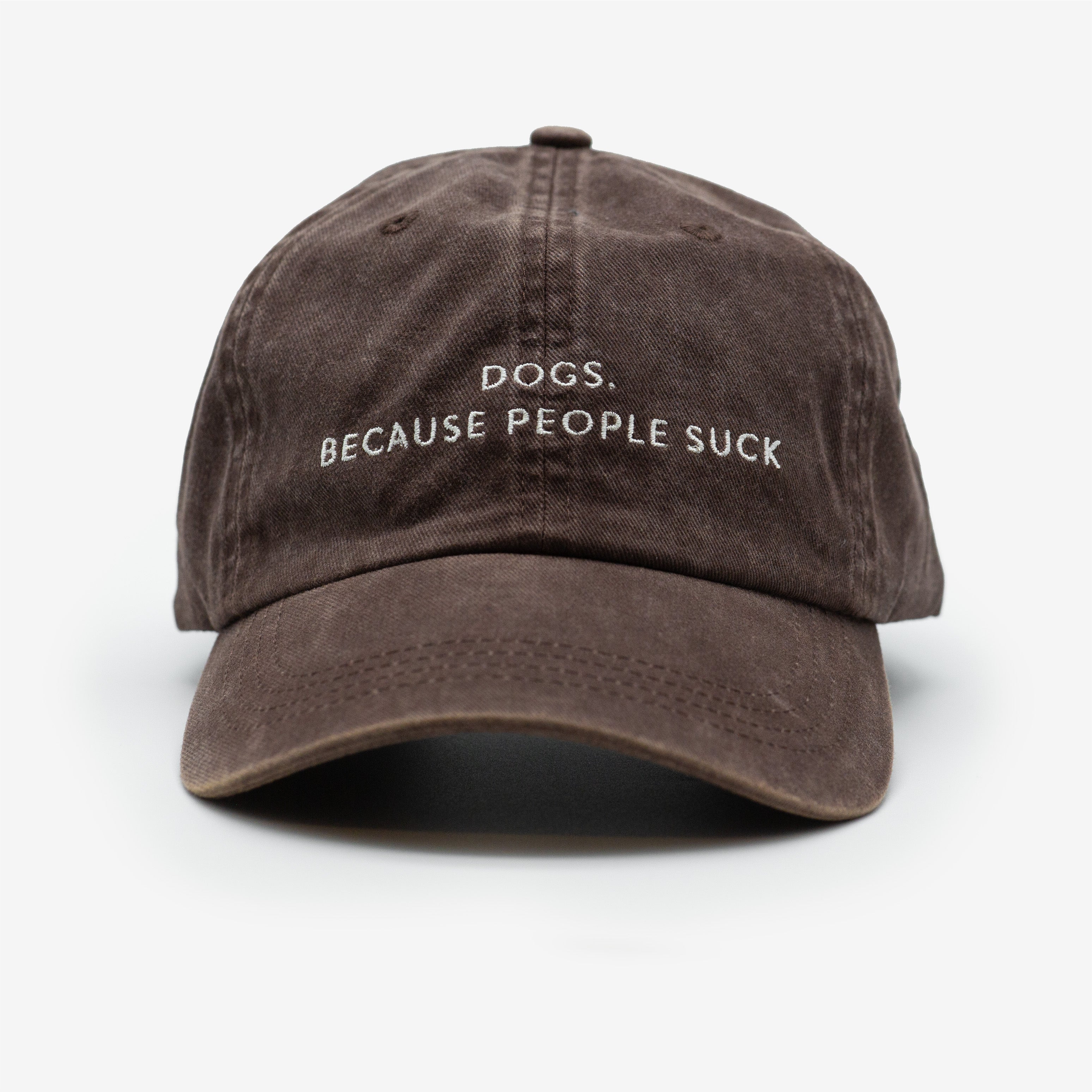A brown denim cap with the text 'DOGS. BECAUSE PEOPLE SUCK' embroidered on the front.