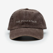 A brown denim cap with the text 'THE DOGFATHER' embroidered on the front.