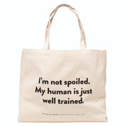 Beige tote bag with the humorous text "I'm not spoiled. My human is just well trained. on a white background